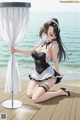 A woman in a maid outfit sitting on a wooden dock by the ocean.