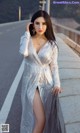 A woman in a silver dress posing on a bridge.