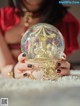 A woman holding a snow globe with a carousel inside.