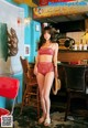 A woman in a red bikini standing in front of a bar.