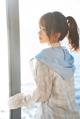 A woman standing by a window looking out at the ocean.