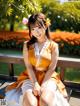 A woman in an orange and white dress sitting on a bench.