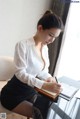 A woman sitting at a desk writing on a notepad.