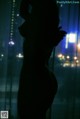 A silhouette of a woman standing in front of a window.