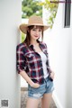 A woman wearing a straw hat leaning against a wall.