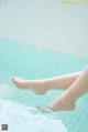 A woman's legs in a swimming pool with her feet in the water.