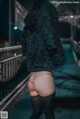 A woman in a black jacket and black stockings standing on a bridge.