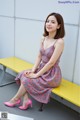 A woman sitting on a yellow bench wearing pink shoes.