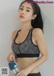 A woman in a sports bra holding a water bottle.