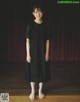 A young girl standing in front of a red curtain.