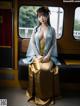 A woman in a blue and gold kimono sitting on a train.