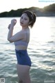 A woman in a blue bikini standing in the water.